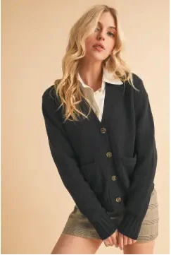 Woman wearing a dark blue cardigan over a white shirt and beige skirt on a beige background