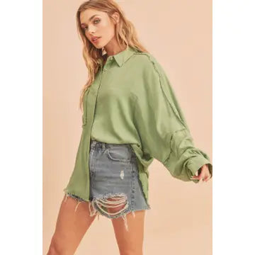 Woman wearing a green shirt and denim shorts on a beige background