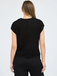 Woman wearing a black textured top against a white background