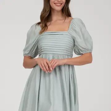Woman wearing a light blue dress with puffed sleeves on a white background