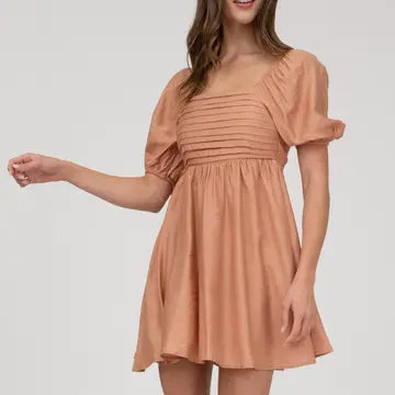 Woman wearing a peach-colored dress on a white background