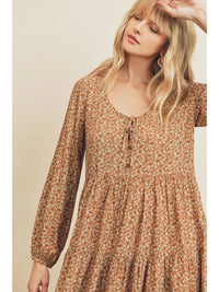 Woman wearing a brown floral dress against a beige background