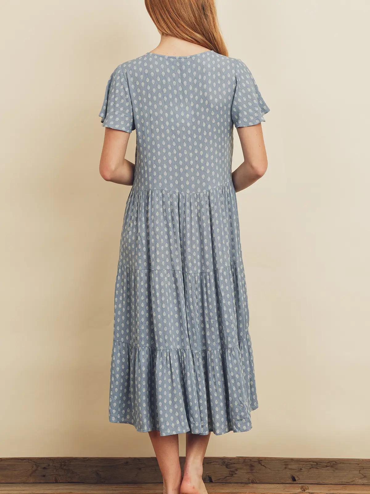 Woman wearing a blue polka dot dress against a beige wall.