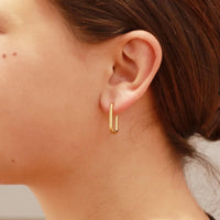 Close-up of a person wearing gold hoop earrings.