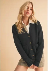 Woman wearing a dark blue cardigan over a white shirt and beige skirt on a beige background