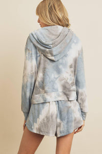 Person wearing a tie-dye hoodie and shorts set on a beige background