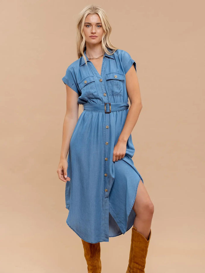 Woman wearing a blue dress with a belt on a beige background