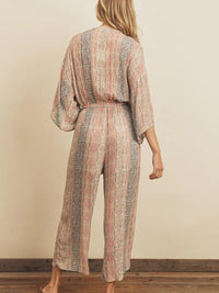 Woman wearing a patterned jumpsuit against a beige wall.