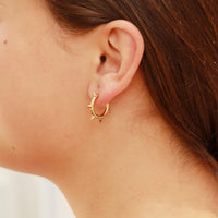 Gold hoop earring worn by a person with brown hair.