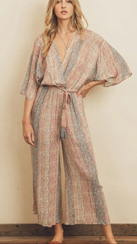 Woman wearing a patterned jumpsuit against a plain background