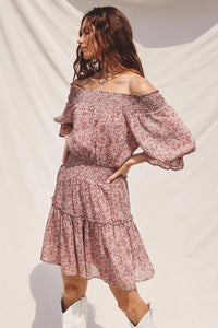 Woman wearing a pink floral off-shoulder dress against a white background