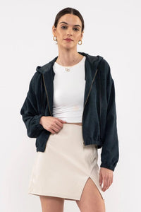 Woman wearing a navy jacket, white top, and beige skirt on a white background