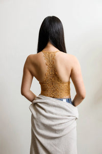 Woman wearing a gold lace top and white skirt against a plain background