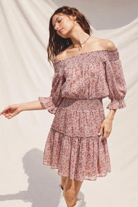 Woman wearing a pink floral off-shoulder dress against a white background