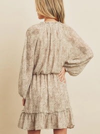 Woman wearing a floral dress with long sleeves on a beige background