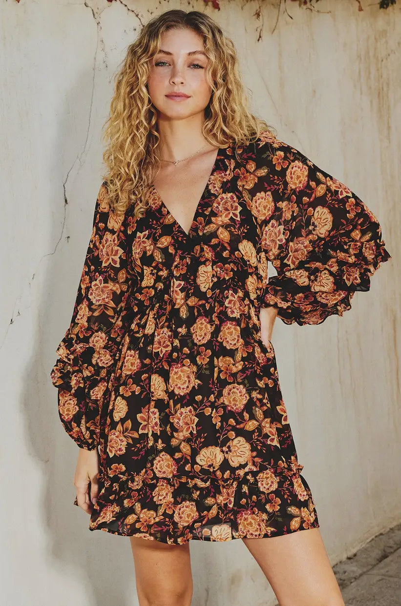 Woman wearing a floral dress against a textured wall.