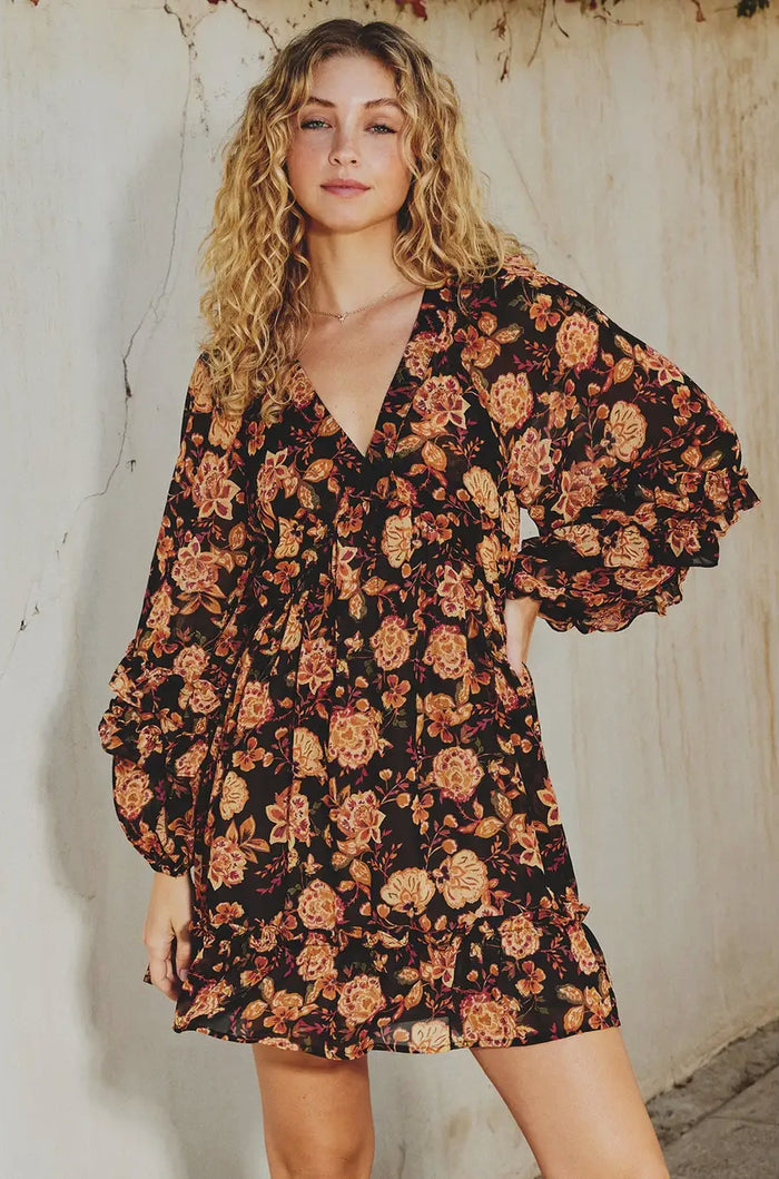 Woman wearing a floral dress against a textured wall.