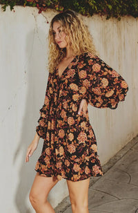 Woman wearing a floral dress against a white wall
