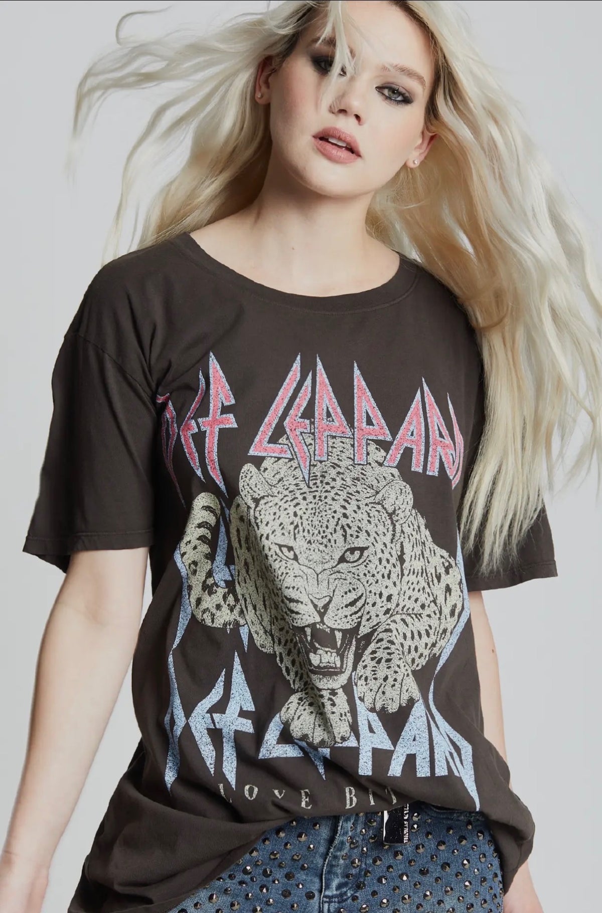 Person wearing a Def Leppard t-shirt with a leopard graphic on a plain background from Cashato.