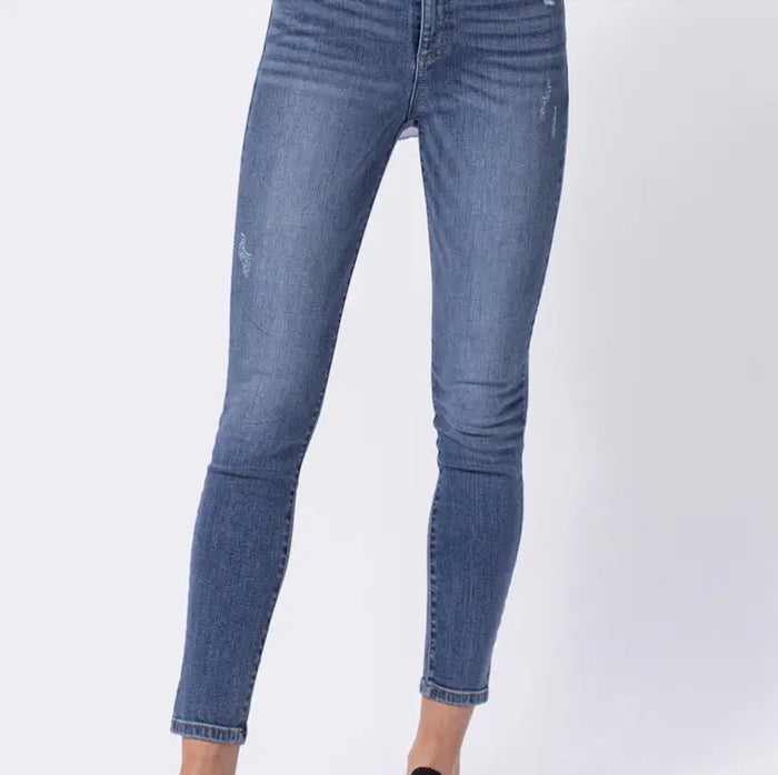 Model wearing Sneak Peek high-rise skinny jeans with light distressing, styled with a white tank.