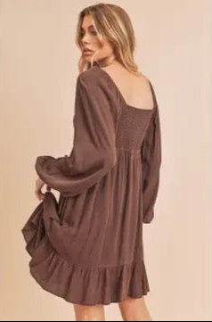 Woman wearing a brown dress with long sleeves on a beige background