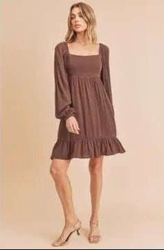 Woman wearing a brown dress against a beige background