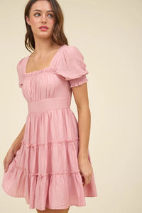 Woman wearing a pink dress against a beige background