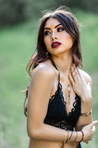 Woman wearing a black lace top outdoors with greenery in the background