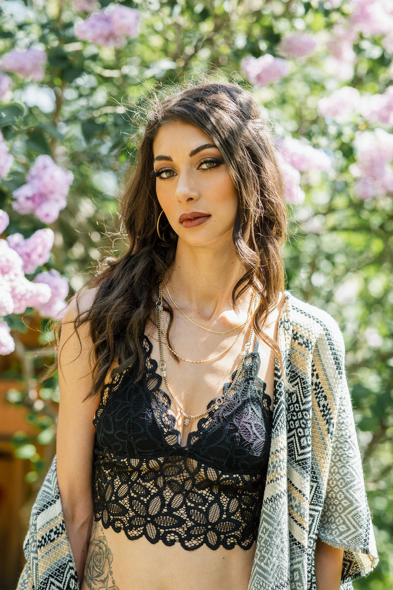 Woman wearing a black lace top and patterned kimono in front of pink flowers