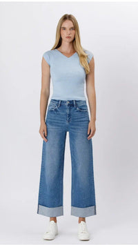 Woman wearing a light blue top and blue jeans on a white background