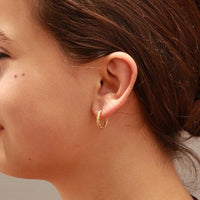 Close-up of a person wearing a gold hoop earring.