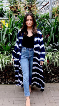 Woman wearing a long blue and white striped cardigan in a greenhouse setting