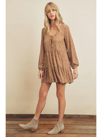 Woman wearing a patterned dress and boots on a plain background