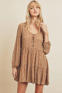 Woman wearing a brown floral dress against a beige background