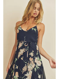 Woman wearing a navy floral dress against a beige background