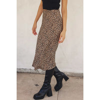 Person wearing a leopard print skirt and black boots against a plain background