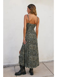 Woman wearing a floral dress with black boots against a white wall.