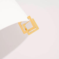 Gold square earring on a light gray background